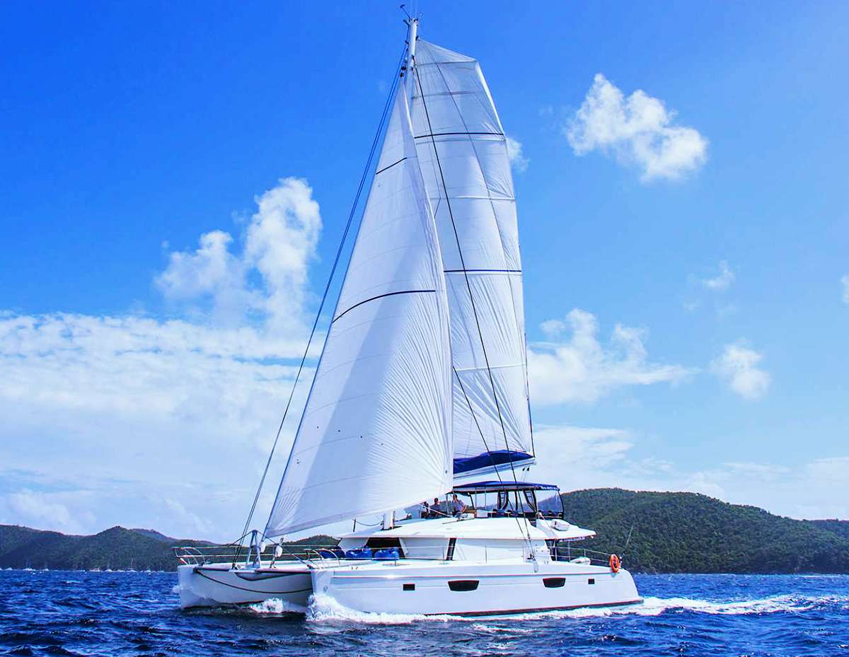 The finest cruising experience yet imagined, NENNE (a Swedish name which means strong and brave like a lion), elevates the enjoyment of a floating holiday to new heights. A Victoria 67, newly built and launched in 2017, she's the newest addition to Fountaine Pajot's Flagship fleet, their top-of-the-line luxury cruising cats. She's sleek, elegant, and extremely spacious with an overall length of 67 feet and beam of 31 feet; truly, the ultimate in cruising comfort.
The popular flybridge concept has been expanded on this yacht to a state nothing short of magnificence. It is accessed from the cockpit with stairs on both sides that are highly secure. The 2-person carbon fibre helm, offset to starboard, provides the captain excellent visibility and easy access to winches, sheets, sails and traveler to ease the work of sailing. For guests aboard who have come to relax, the seating area is incredibly comfortable with benches, side tables, a relaxing sofa, and the convenience of a refrigerator and sink. The rise & fall tables can also be used for dining, making this a highly usable area not usually found on an FP 67. A large bimini provides an area of escape from the sun for those who want some shade and there is integrated lighting for evening cocktails. Additional side and rear covers can be used to block the wind for dining if desired, and of course, the large double lounge cushion for sun bathing make this a highly desirable space for the ultimate in relaxation, all enjoyed with awesome views of the surrounding scenery.
The large aft deck is shaded by the flybridge overhead and provides additional comfortable lounging spaces, as well as an elegant setting for formal dining. Two large sumptuous pads are optimal for relaxing. A projector and large cinema screen can be viewed inside from the cockpit or saloon.
Step into the saloon which features urban chic decor with gorgeous leather upholstery, and lots of space for comfortable entertaining in air-conditioned comfort if so desired. The large relaxing seating area has an electric rise and fall coffee / dining table providing an additional option. The open galley is equipped with state of the art appliances, fine china, and extensive glassware. There is an extra chart plotter and helm station at the chart table from where the boat can be steered.
Accommodation for 10 guests in 5 cabins which are all en-suite: 1 King, 3 Queens, and 1 Twin which can be configured to a King upon request. Each cabin has independent A/C, Sony and Apple flatscreen LED TV with access to onboard server film library with over 500 films, Bose hifi music system, high quality bed linens and and towel sets including nice thick NENNE-branded beach towels. The very large primary cabin has a desk/dressing table and a comfortable couch.
NENNE is equipped with a large array of water toys including, snorkel gear, kayaks, stand-up paddleboards, wakeboard, adult and children's waterskis, a range of towable inflatables, plus a Yamaha 70hp tender for towing. For guests interested in scuba diving, you won't find a better choice than NENNE as she offers a premium dive experience with a complete assortment of top-of-the-line equipment, an onboard dive compressor. (See specs for details.)
