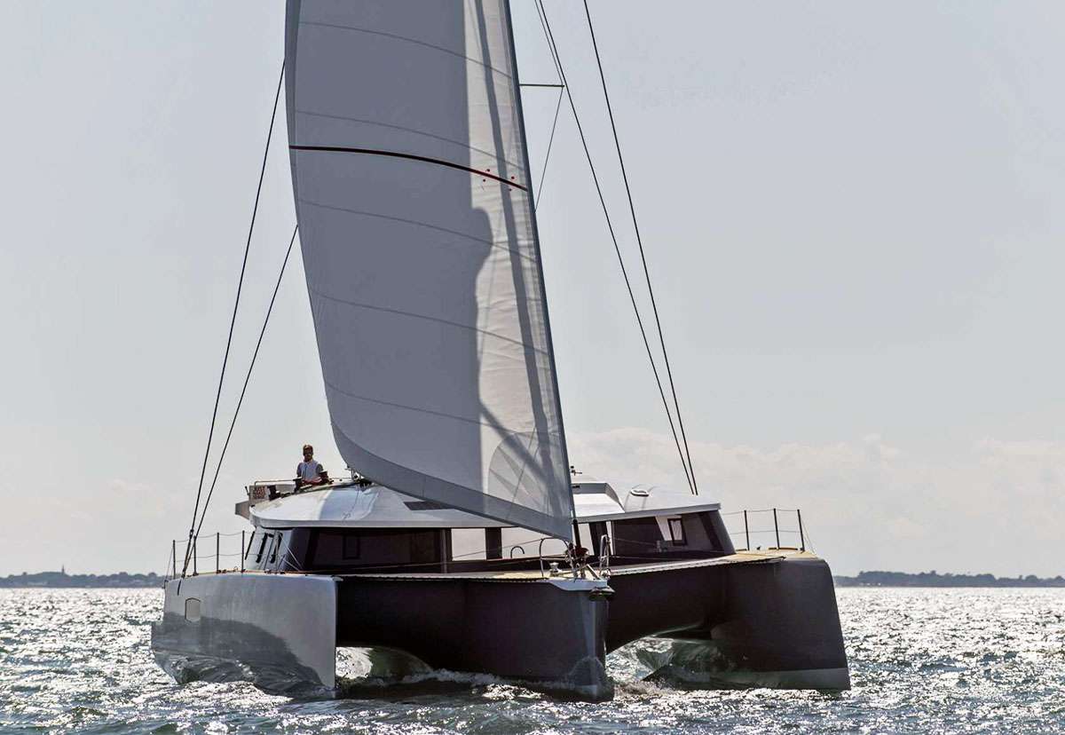 Trimaran TRILOGY emerged from the French builder Neel in 2017. This bluewater yacht is in a class of her own. She is the cutting-edge option for charter guests who crave the thrill of performance sailing, but require the living space of a much larger motor yacht. 

Thanks to her triple hull construction, her super-wide, 29-foot beam is the average equivalent of a 130-foot superyacht build. This means that together, the entire charter party can enjoy panoramic views from the main saloon, sprawl across the giant trampolines, or lounge on deck. Alternatively, everyone can have their own quiet space to read, relax, sun and commune with the sea.

The cockpit, protected by a hard bimini, is equipped with a fridge, grill and sink. Guests can relax on a pair of banquettes that stretch across the stern, or take a seat at the teak table, which seats eight, to dine al fresco. Steps away, the swim platform provides easy access to play in the sea.

The literally &ldquo;open&rdquo; architectural design of the main deck features sliding doors that stow away completely to unite the cockpit and interior saloon into one seamless, breezy space. There is a surround of large windows that add to the sensation of a floating villa. The en-suite primary cabin is uniquely positioned on this deck level. The amazing picture window, a wall of glass at the foot of the bed, provides a mesmerizing view. 

Three additional guest cabins are located below. The center hull has a double v-berth forward with bathroom located a few steps down. Two other guest cabins with queen berths are positioned aft in the port and starboard amas/hulls (outriggers), with toilette/shower facilities in the bow. 

TRILOGY is a fast boat. The yacht skips effortlessly over the waves and is designed to cruise at 10 knots in a breeze, faster depending on the sails and conditions. For a yacht charter that combines sailing performance with the ultimate in luxury accommodations, TRILOGY is a dream come true.

Photo copyright in this brochure: Nicolas Raffi / NEEL-TRIMARANS

