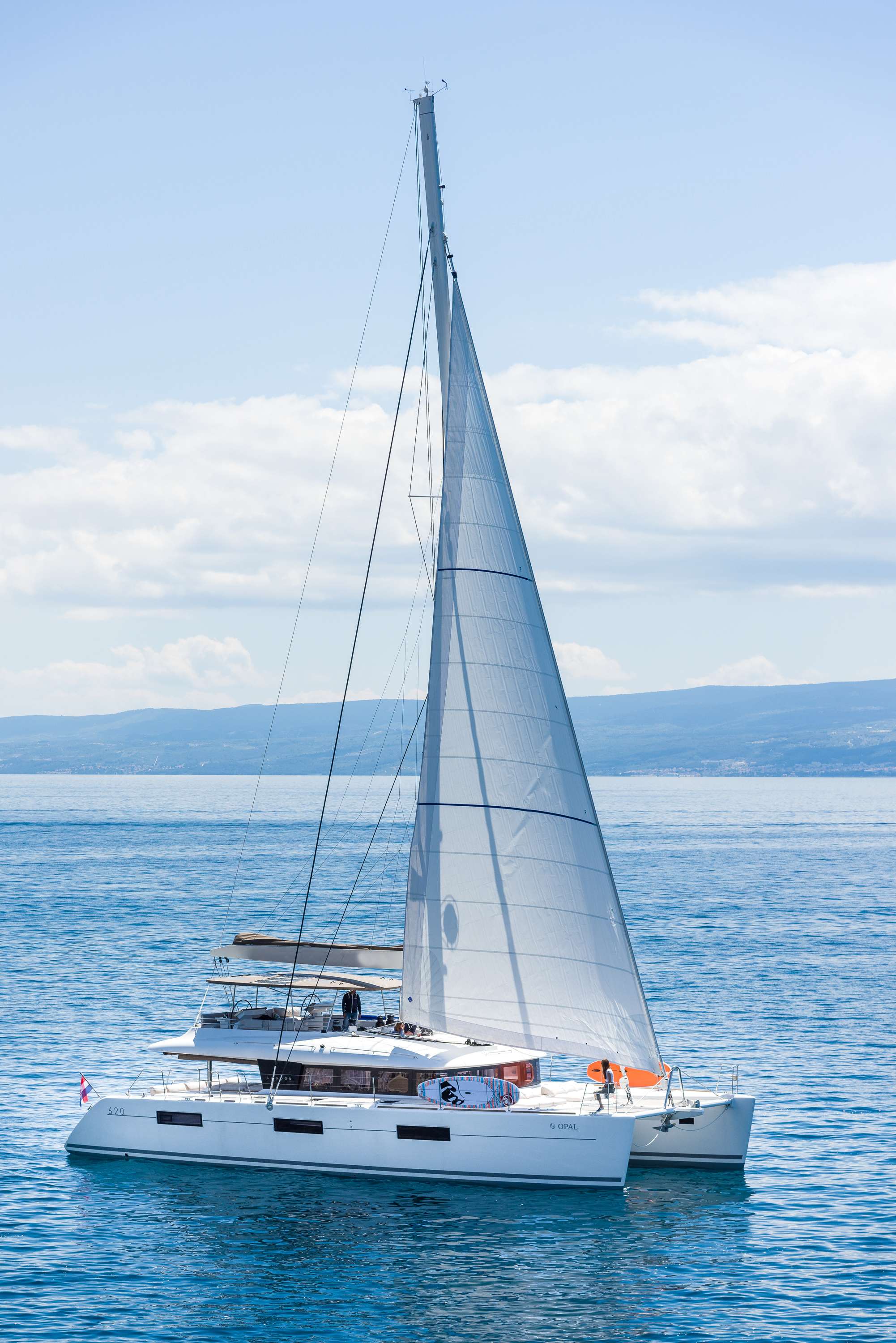 New Lagoon 620 is designed to meet the needs of today’s cruising yachtsman: strength, comfort, performance and exceptional living space. Ideal for clients who want to experience the art of living aboard in an innovative way.
OPAL, available for charter in Croatia, can accommodate up to 10 guests in 5 double cabins – all en-suite, plus saloon with separate cabins for three professional crew members (captain & stewardess and professional chef).
Complete interior layout is elegantly incorporating wood finish, upholstery, inner liners, and more. A functional fly bridge can also accommodate guests thanks to separate crew and reception areas. Saloon and cockpit are beautifully integrated and include “wet bar”, areas for lazing around and the option on taking delicious meals inside or out without having to make any adjustments.