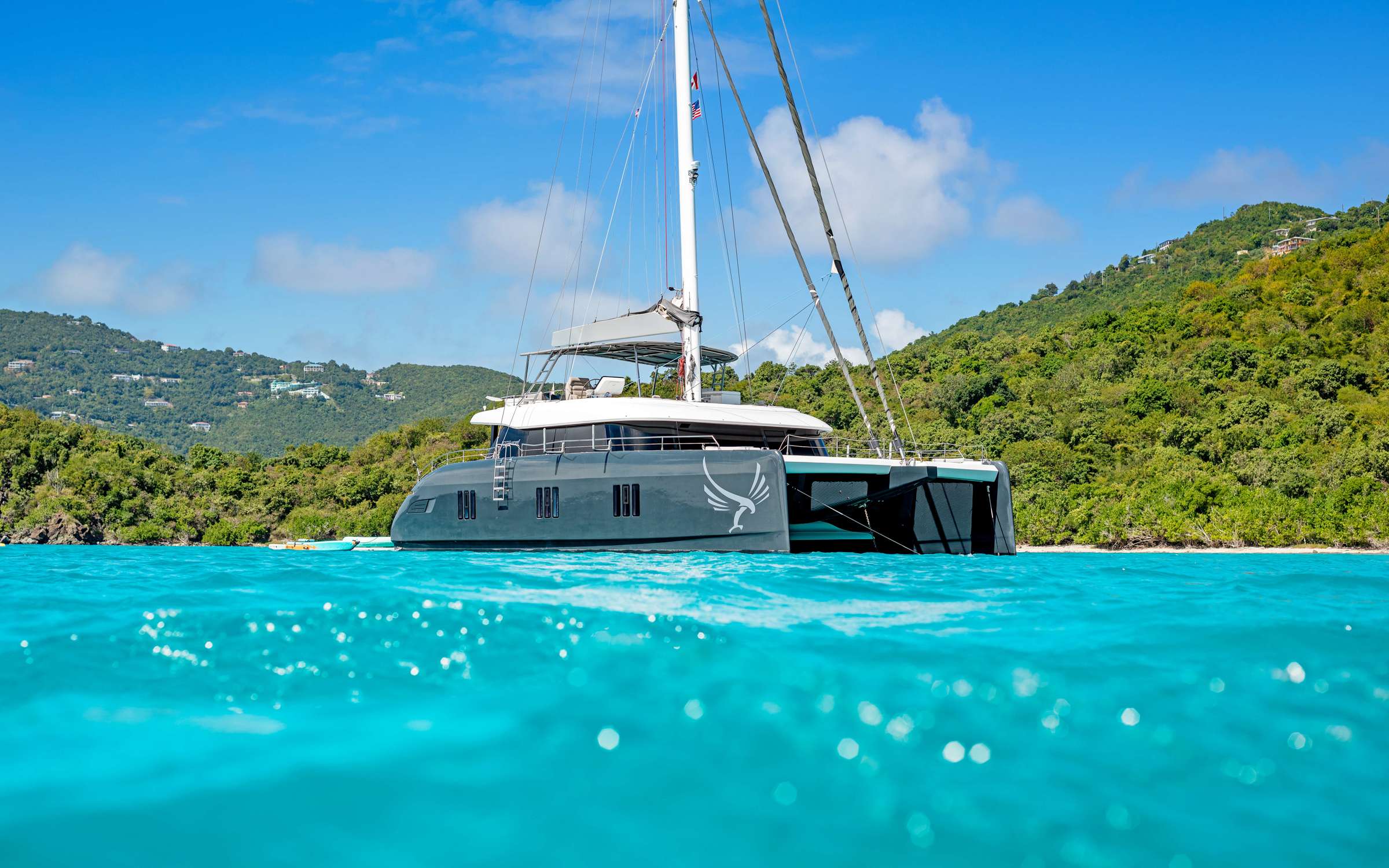 Superb and elegant, GYRFALCON is a luxurious sailing Sunreef 60 catamaran launched in 2019. Destined for sailing adventures in ultimate comfort, GYRFALCON boasts a combination of exterior and interior areas easily flowing into one another.
Her smart and well-designed layout offers sumptuous accommodation for 10 guests. Perfect to unwind and relax after a long day in the sun, five elegantly appointed en suite cabins with comfortable queen beds are designed in a soothing white and grey colour pallet.
A generous saloon combined with a functional galley opens both onto the bow terrace and cockpit creating one huge lounging area. Decorated with bright powder blue accents, the saloon is equipped with a big unfoldable table and comfortable seating for 10, allowing guests to dine in comfort and relax in a homelike atmosphere.
GYRFALCON features exterior spaces that are impressively vast and perfectly equipped for an unforgettable charter experience. The yacht’s flybridge is ideal for revelling in pleasant sea breeze and spectacular views. Fitted with large sun pads, coffee tables, pouffes and a bar, it is the ultimate place to spend relaxing afternoons. Guests will also enjoy an additional terrace in the front benefitting from a cosy lounge which can be shielded from the sun.
Operated by three outstanding crew members, GYRFALCON gifts an unparalleled experience in the world’s most attractive yachting destinations.