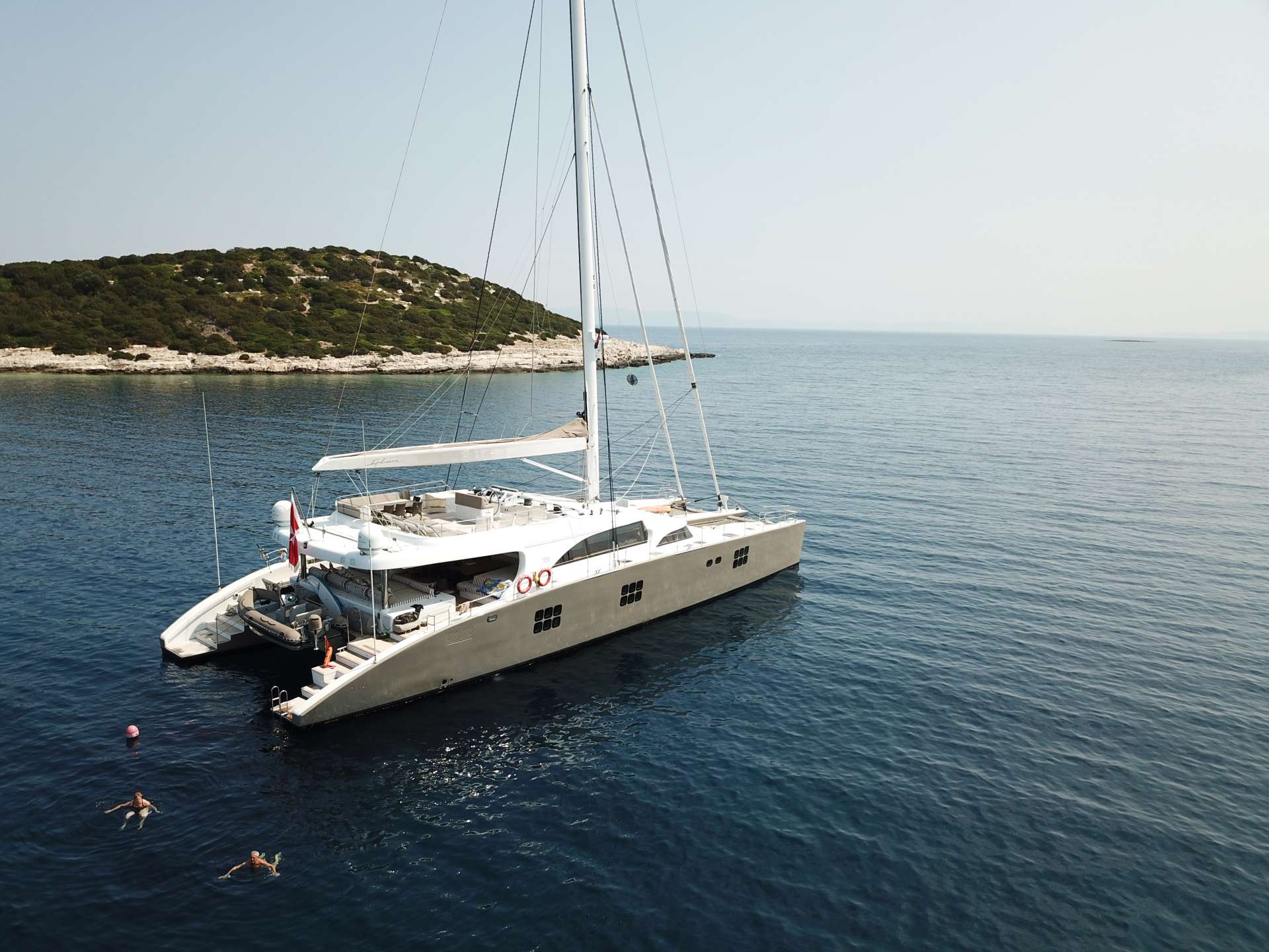 IPHARRA the 102ft super luxurious Sunreef catamaran, launched in 2010 continously impresses charter guests with her splendor and stability.
IPHARRA’s interior greets guests with a warm and romantic atmosphere. This is enhanced with the custom designed light and dark contrast of wendge and arengre woods. The combination accentuates the geometric shapes of the surrounding furniture. Beige, cream, and ivory colors subtly catch the eye bringing a balance to the soothing design features. Generous views are offered through IPHARRA’s magnificent windows stretching around the main salon area. There is adequate space for all guests to peacefully lounge.
Featuring 5 state of the art guest cabins, IPHARRA is capable of accommodating up to 10 guests comfortably. Guest staterooms include 1 Master cabin with a king size bed, 2 VIP cabins with queen size beds and 2 twin cabins. The stylish staterooms are all enhanced with Bose audio system, LCD TVs, and ensuite facilities.
A fully equipped galley provides all the essentials to cater to your charter needs; including a full size stove, fridge, dishwasher, and wine cooler. The open area is the perfect spot to enjoy the chef’s creative cooking style.
Setting sail on IPHARRA, guests have plenty of comfortable options to enrich their charter experience. The adventurous guests will find refuge on IPHARRA’s spacious flybridge. Here the navigation station is centrally located, and all maneuvering can be accomplished with her high tech hydraulic winches, bow thrusters and magic trim installed by the mast. The flybridge also is equipped with a bar, large sofa, and deck chairs providing guests the freedom to lounge in the shade or tan in the sun.
Down IPHARRA’s spiral staircase guests are welcomed with cozy oversized sofas and large dining table on the aft deck. This is the ideal venue for both dining and relaxing in luxury with up to 10 guests. As the sun sets, the LED lights on the ceiling sparkle magically in the night.
IPHARRA has a full selection of water toys for charter guests to take advantage of. Options include waterskies, sailing laser vago, 2 electric seabobs, 8 sets of diving equipment, 1 kayak and snorkeling gear. IPHARRA offers two tenders available for use as well.