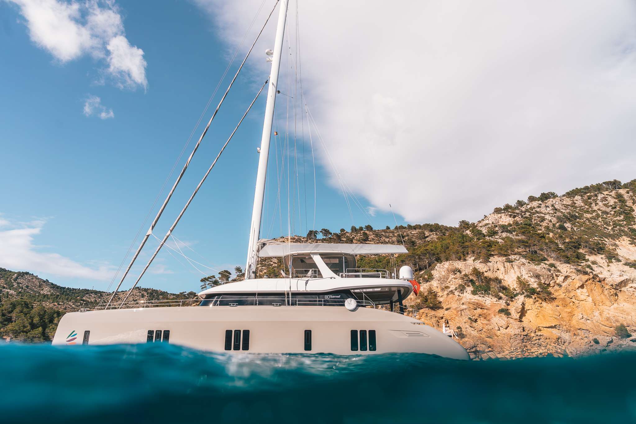 VIVA LA VIDA is a newly built Sunreef 80 depicting wellness and comfort on board. Highlighting eco solutions for more sustainability, she is fitted with solar panels helping to reduce the usage of generators and keeps a recycling and composting system, while reducing plastic use as much as possible. This striking catamaran will be sailing in Western Mediterranean this summer.
Inside the vast salon, a wooden floor and high-end bespoke décor and furniture were combined with taste. Down the hulls, there are 4 finely appointed cabins, all featuring en-suite facilities, that allow for 8 guests to be accommodated in double beds and 1 guest in pullman bed.
Outdoor spaces were made for lounging and enjoying the views of the sea in absolute comfort, with multiple sun shade areas thanks to carbon poles. The flybridge hosts a wet bar, various sunpads and a large dining area. Another alfresco dining space is located on the aft. On the bow terrace, we can find a comfortable lounging space and trampolines.
One of the yacht’s assets is definitely her passionate crew of 4.
Chris, the Captain, has a long experience in sailing catamarans and will be delighted to assist the guests during the trip, whether sharing his knowledge of the sea or helping with the variety of water toys.
There is also the possibility to hire a 5th crew member upon request.