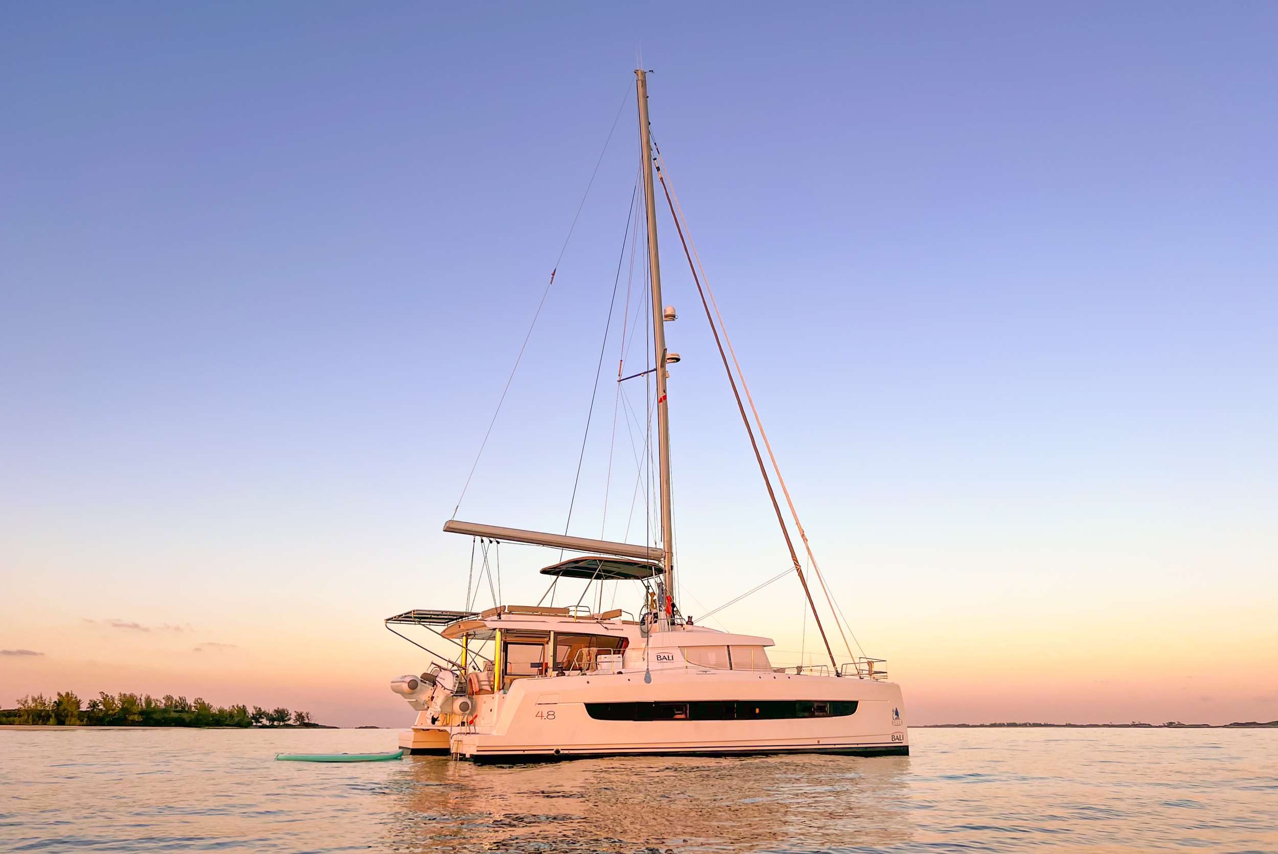 The Bali 4.8 design was new to the market in 2020 and provided a fresh approach to sailing. The design is revolutionary in how space is accessed, with deliberate attention to flow and open space.
It succeeds in producing a scale that feels less like a boat, and more like an upscale floating condominium.

Bali catamarans are known and appreciated for their unparalleled success in blending luxury, space, and performance; producing a sailing experience that is unparalleled.
This new design further capitalizes on that reputation with the advent of the “Bali garage door” that is the centerpiece of the yacht. It allows for the aft wall of the yacht to simply disappear, opening up the back of the yacht to an unobstructed view of paradise. This also affords indoor/outdoor dining options and gives the ever-
present Caribbean breeze ample opportunity to make its way through the yacht with ease.

With her solid foredeck gone are the forward trampolines, replaced by a large relaxing lounge area complete with cushions for sunbathing. A full- sized door provides access directly from the lounge area into the salon, allowing free movement through the yacht. A walk up to the flybridge unveils a seating area perfect for cocktails and taking in sunsets.
There is also another area for sunbathing on the flybridge where you can take in the sights of the islands from the highest vantage point on the yacht.

The Bali open space design is further complimented by the superior outfit of Bella.
No detail has been left unnoticed from the fine linens, pillows and throws to the wine glasses, serving and
flatware that make every day feel luxurious. She has been stocked full with every appliance and kitchen accessory to allow the chef to fully showcase the mastery of their art.
And the water toys abound, allowing guests to fully experience all the Caribbean has to offer, both in and out of the water.

Bella will accommodate 6 charter guests in 2 spacious queen cabins and 1 sprawling owners suite master cabin for those who desire more space. She has solar panels, air conditioning, water maker, ice maker, full-sized refrigerator, a fully customizable menu, Caribbean made eco-friendly and reef safe toiletries, a bar stocked to guest preference, coffee/espresso machine, rendezvous scuba diving, snorkeling gear, underwater scooters, sub wing, wakeboard, stand up paddle board / kayak, towable water tube, 10 ft. floating dock, pool noodles, fishing gear, board and card games, television in the salon, Fusion 3 Bluetooth enabled sound system and Bella giveaways.