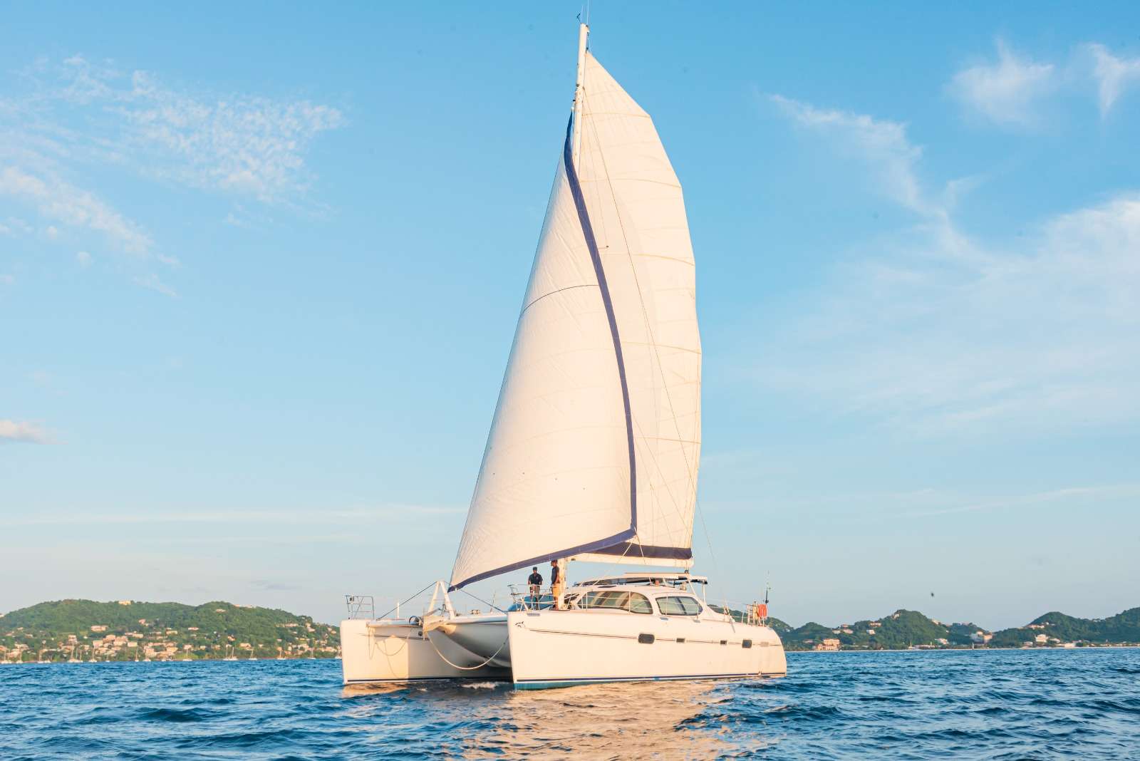 Lady Marigot is named after what the novelist James Michener called 'the most beautiful bay in the Caribbean' - Marigot Bay, Saint Lucia. She is a spacious Privilege catamaran with an elegant finish, comfortable seating, and excellent sailing performance... our ship sails quick! What is more, since the boat rests high above the water, fewer waves splash against the bottom resulting in a smooth and speedy sailing experience.
For guests who are looking to explore sheltered cays, quiet beaches, vibrant coral reefs, and bustling tropical markets, Lady Marigot and her crew will take you on an unmatched adventure to both the hidden gems and popular destinations of St. Vincent & the Grenadines, the Windward Islands, and beyond!
The captain and two crew, with years of hospitality and onboard experience, provide a truly authentic Caribbean charter. Each from St Lucia, all three have spent their lives sailing there, the Grenadines, and the Lesser Antilles. All of our crew have worked with Lady Marigot for over six years (relief-crew included!) and our chef has been with us for ten.
Lady Marigot's spacious decking offers sunbathing mattresses located either side of the cockpit; bean bags, trampolines, and plenty of room further forward; two seats at the bow to enjoy a glass of wine & watch for dolphins; and comfortable, unforgettable elegance all around! For active guests, there are tubes, inflatables, towable toys, snorkeling gear, yoga mats, and paddle boards. A 50HP tender allows for speeding to the smaller islands and beaches, such as the Tobago Cays' Turtle Sanctuary or the beachside lobster BBQ.
On entering the interior, the cherry-wood saloon has plenty of light, multiple seating areas - for coffee and dinner - a large TV, sofa, and a well-placed wet bar for the crew to prepare drinks and cocktails. With the galley down in the starboard hull, guests will have even more room to socialize and relax. Typically, guests dine outside in the expansive cockpit seating area.
There are two King and three Queen cabins onboard. All cabins in Port and Starboard hull have ensuite dry shower and separate head. The cabins are spacious with plenty of storage, air conditioning, and child safe fans. Two crew would typically stay in the central queen cabin while the captain has his own separate accommodations forward.
During 2022 - 2023 Lady Marigot has been equipped with new teak decks, new windlasses, new galley equipment, a new hull gelcoat, new rubber seals, new linens, new towels, and additional new water-sports equipment. In 2024 she received new hatches, new tender engine, new interior paneling for cleaner/fresher look, new kevlar rigging, upgraded galley and new propellors for faster motor sailing.
Lady Marigot has been designed as a fast, luxurious yacht offering an opulent interior space, beautiful lines, and flat uncluttered decks with plenty of room to sunbathe. Sailing performance should not be overlooked - she will match and outpace even the lightest of catamarans on the water.
Regardless of whether you are young at heart or old in spirit, we will craft the ideal, bespoke charter for you based on years of travel and nautical experience... Lady Marigot awaits!
